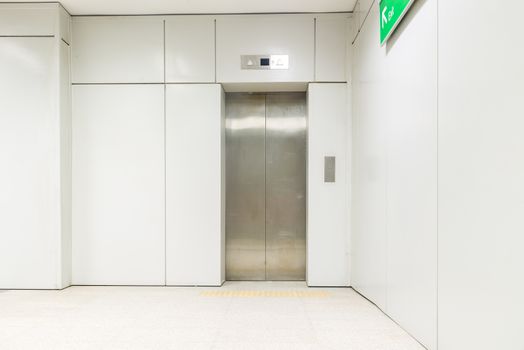 An empty modern elevator or lift with metal doors that are open in building with lighting.