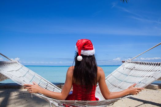 Woman in hammock on tropical beach celebrating Christmas