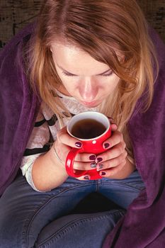 Girl sitting on sofa in livingroom with cup of tea