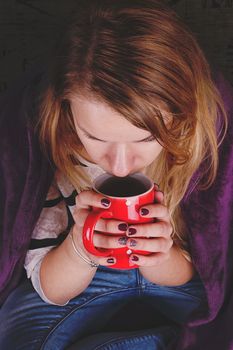 Girl sitting on sofa in livingroom with cup of tea