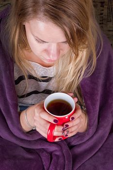 Girl sitting on sofa in livingroom with cup of tea