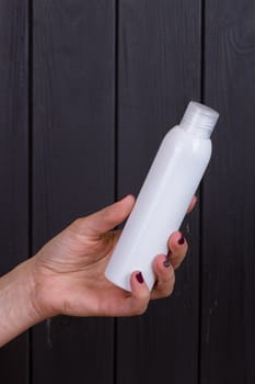 Woman's beautiful hands with care cream tube on the black background