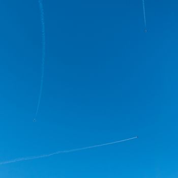 Three planes fly to different sides and leave a smoky trace in the sky.