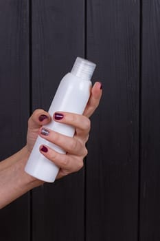 Woman's beautiful hands with care cream tube on the black background