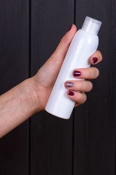 Woman's beautiful hands with care cream tube on the black background