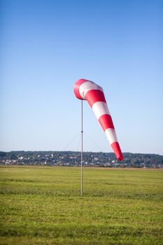 Windsock in a background of the green field and a grass at a light breeze.