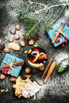 glass of mulled wine on dark Christmas background with boxes of Christmas gifts and spruce branch