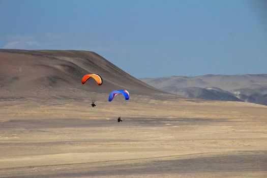 Paraglider soaring over the cliffs at oceanfront of Paracas Peru