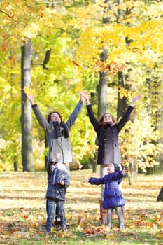 Happy family playing with autumn maple leaves in park