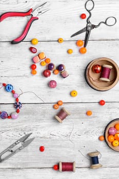 Round beads for bracelets and necklaces on white wooden background.View from the top