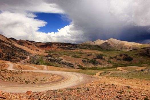 A gravel road going trough the olorful highlands and mountains of southern Peru