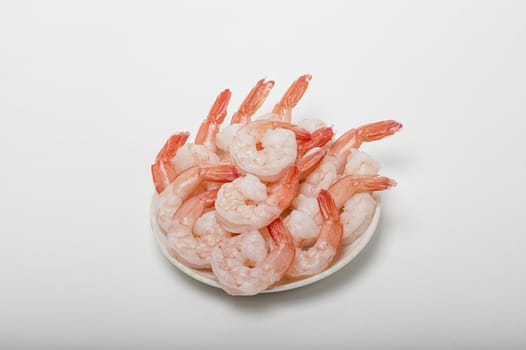 Red peeled prawns lie on a saucer isolated on white background