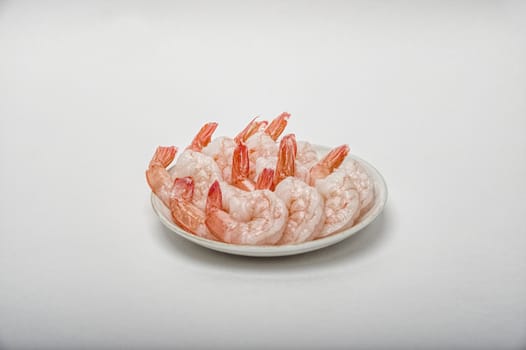 Red peeled prawns lie on a saucer isolated on white background