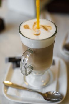 Coffee latte with a thick Crema and yellow straw in a restaurant