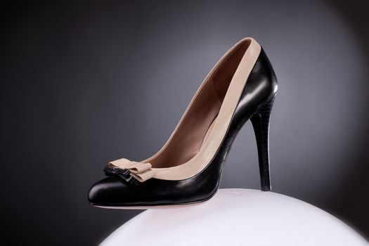 Woman's shoe standing on shiny sphere