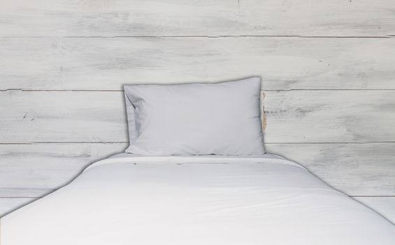 Close up white bedding sheet and pillow with white wooden wall texture background