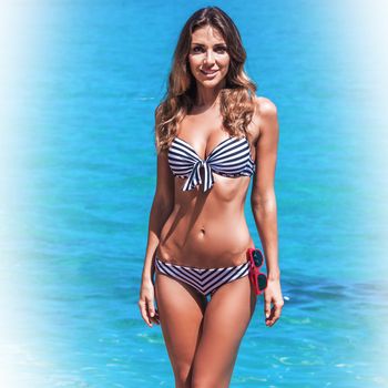 Beautiful slim woman in bikini at seaside
