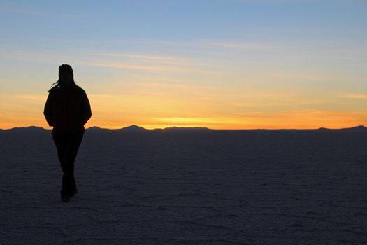 Woman walking on Salar de Uyuni, salt lake, is largest salt flat in the world, altiplano, Bolivia, South America