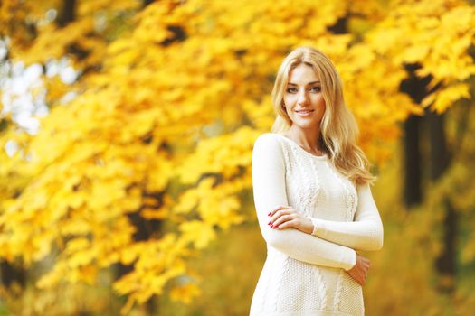 Portrait of beautiful young woman walking outdoors in autumn park