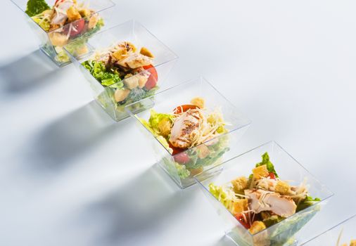 Salad with chicken and crackers in glass on light background