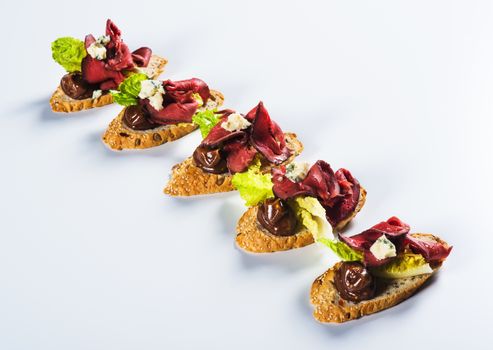 Bruschettas with beef and cheese on light background