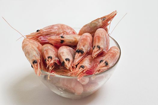 Red peeled prawns lie on a saucer isolated on white background