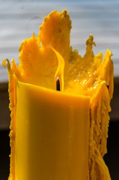 Yellow candle with flame and melting wax