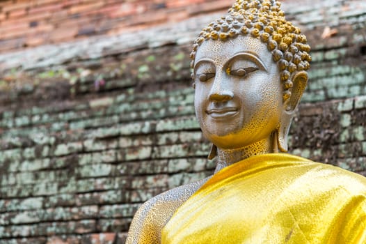 Old Buddha statue with brick wall background