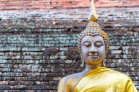 Old Buddha statue with brick wall background