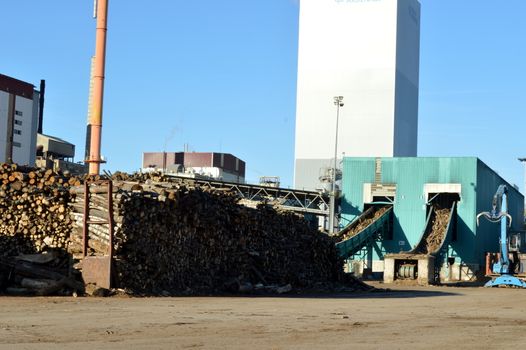 Pulp mill with two fireplaces, wood and a blue sky