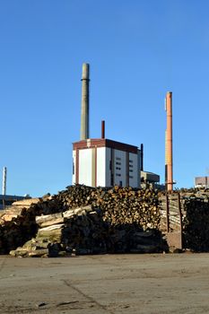 Pulp mill with two fireplaces, wood and a blue sky