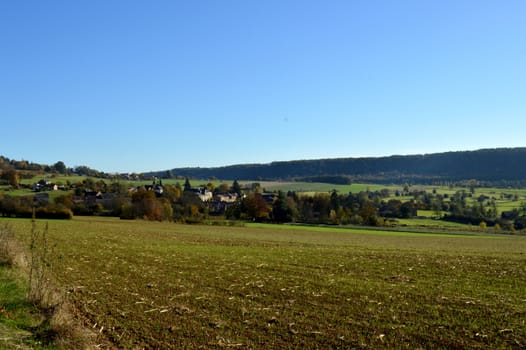 Plow fields with a background hill and a village