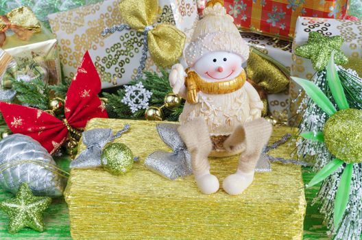 Christmas arrangement in green and gold tones. Cheerful Snowman sits on gifts, Christmas decorations.