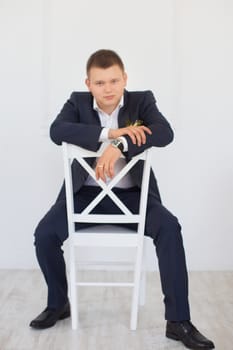 A man in a business suit sitting on a chair in the apartment