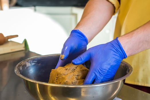Hand knead dough with gloves in a bowl. Preparing cakes