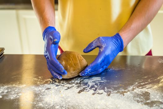 Hands knead dough with gloves on the table. Preparing cakes