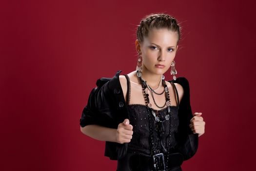 Young woman in a black clothing on a dark-red background