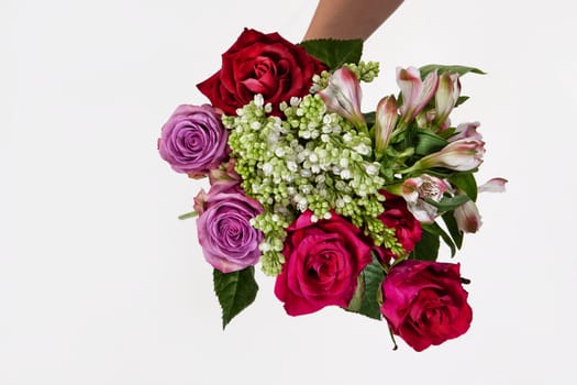 Hand holding a bouquet of different flowers on an isolated studio background