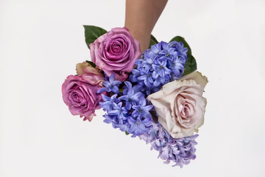 Hand holding a bouquet of different flowers on an isolated studio background