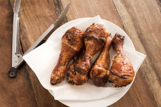 Spicy marinated chicken drumsticks or legs grilled to perfection and served on paper on a plate as a finger snack