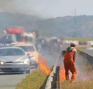 A road worker is putting up a fire caused traffic jam on a highway.