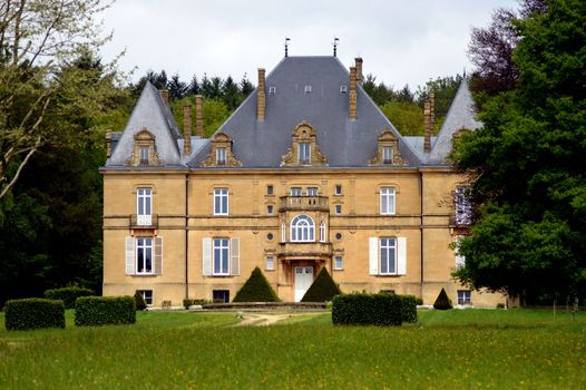 Former castle in the forest with a path of trees and a big lawn.