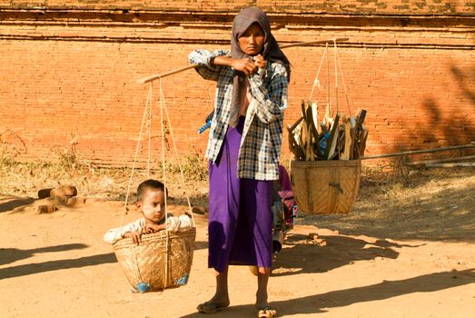 Bagan, Myanmar - 24 January 2010: Woman with her son on a basket at the archaeological site of Bagan on Myanmar