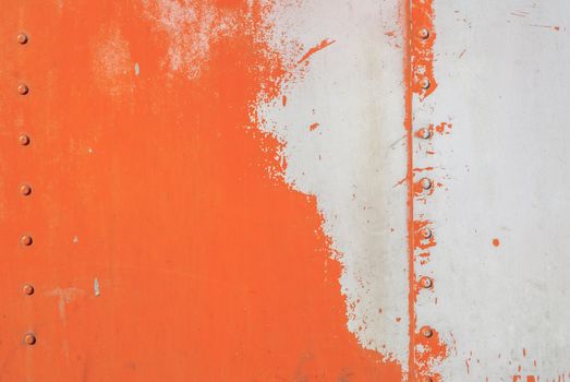 fragment of an iron surface is covered with orange and grey color paint, which has long been under the influence of different climatic conditions
