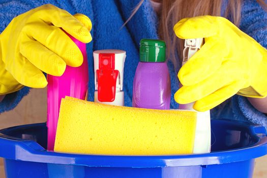 close-up of caucasian woman holdinh basin with cleaning supplies