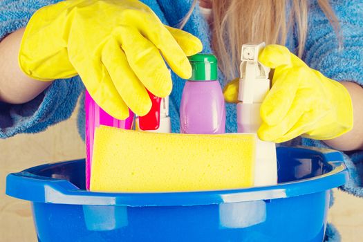 close-up of caucasian woman holdinh basin with cleaning supplies