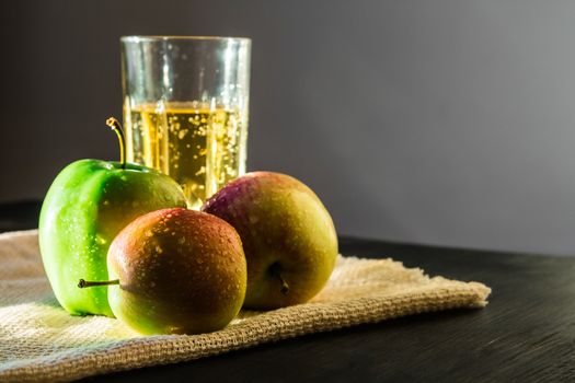 Fresh apples and a glass of sparkling apple wine on canvas napkin in the natural sun light