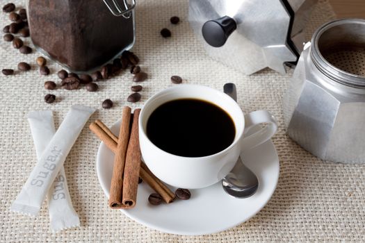 Cup of black coffee with italian coffee pot on flax fabric, top view