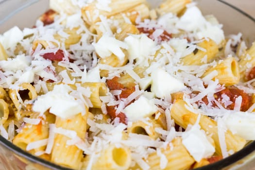 Baked tortiglioni pasta with tomato sauce, mozzarella cheese and parmesan cheese in glass bowl