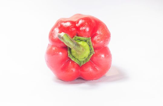 Red pepper on white background with green tail.  Front view